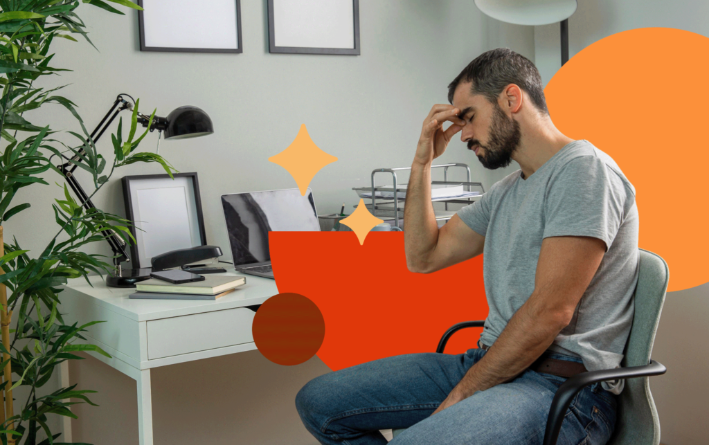 Homem sentado em uma cadeira de escritório em sua mesa de trabalho, de olhos fechados e pressionando a testa com a mão, demonstrando exaustão, estresse e ansiedade associados à autossabotagem no ambiente corporativo.